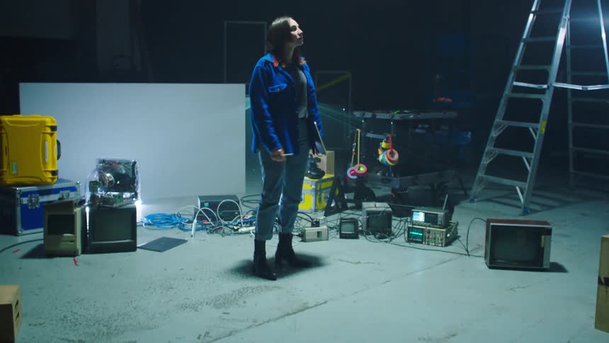 A white woman walks across a dolly track and writes in notebook