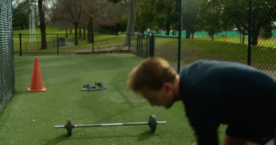A man picks up a medicine ball and throws it forward