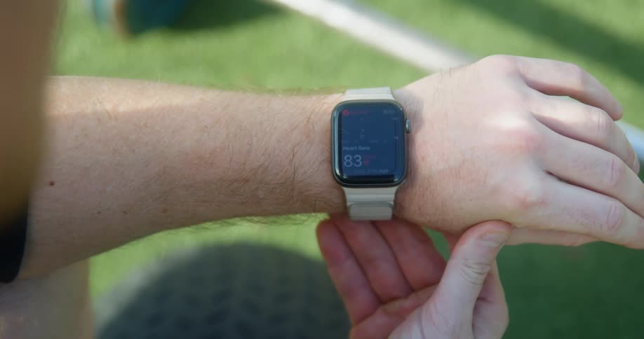 A man sitting outdoors checks his heart rate using a smartwatch