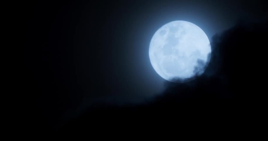 Clouds pass over full moon shining at night