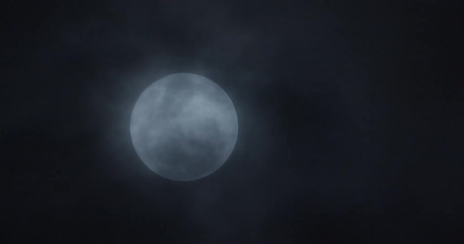 Clouds pass over full moon shining at night