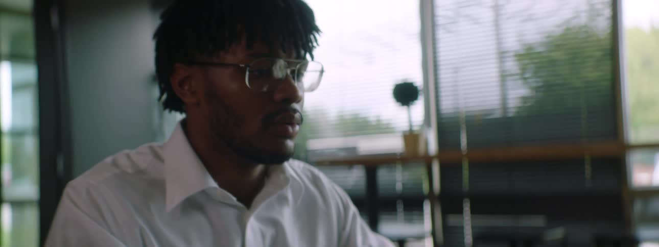 A black male sitting at a table typing on a laptop