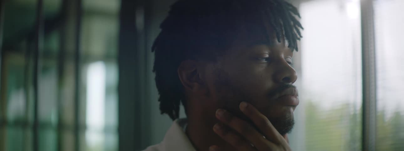 A young man in his office rubs his chin as he thinks