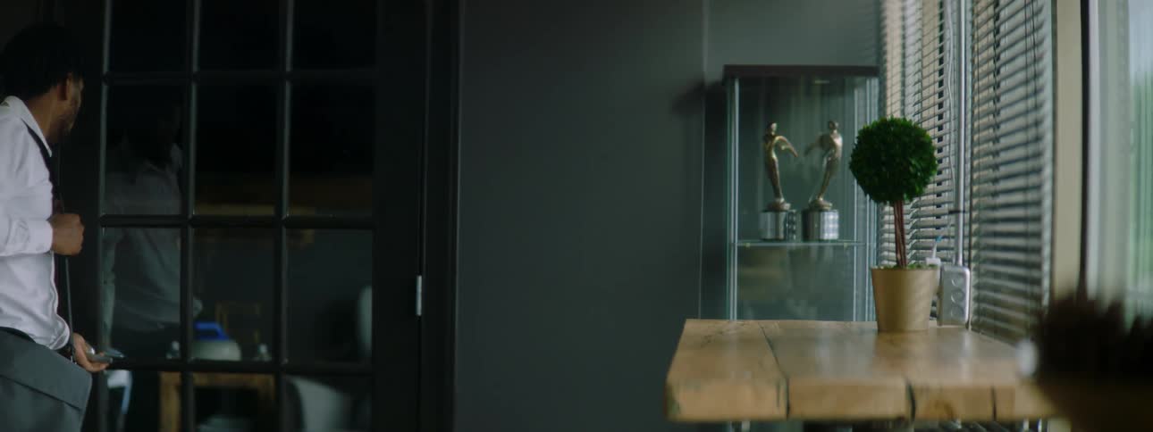 Young man open and closes a glass door to enter a room to sit in a desk