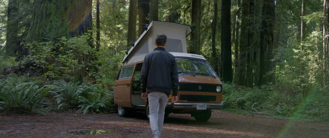 Man walking towards camping vehicle in the woods