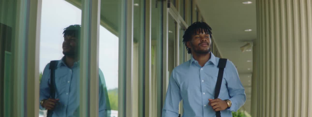 A young black man walking outside an office building