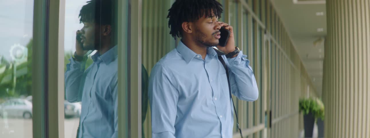 A man is talking on a cell phone next to a building