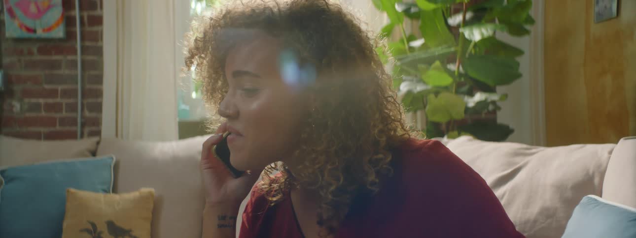 A teenage girl at home holds her laptop and talks on her cellphone