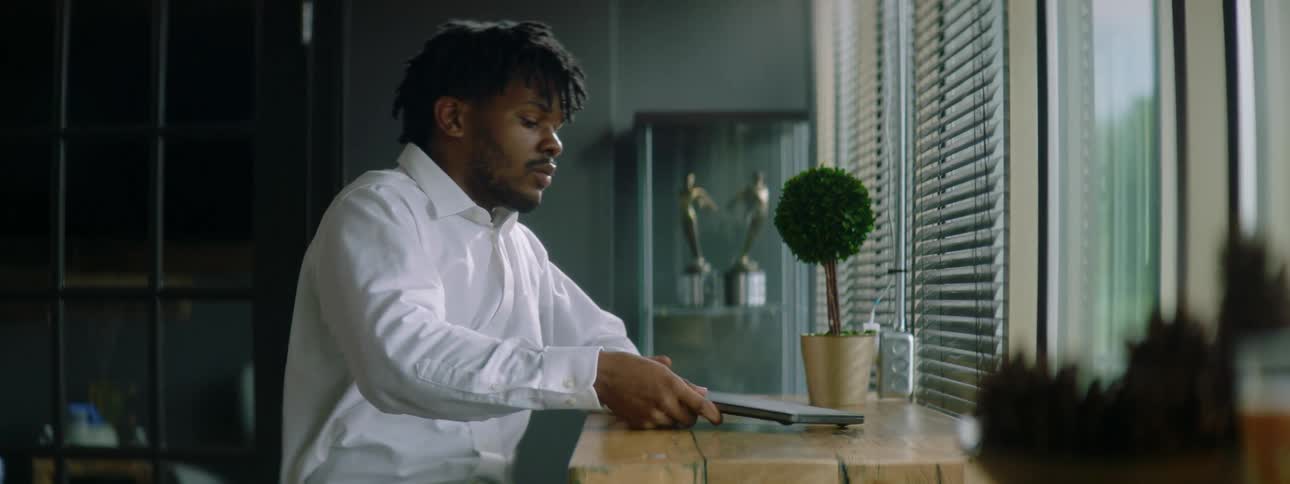 Young man sitting in a desk at home takes a laptop out of a bag