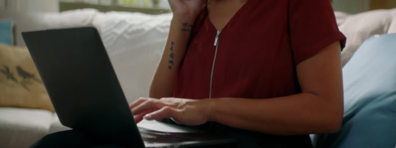 Woman talks on mobile phone while typing on laptop
