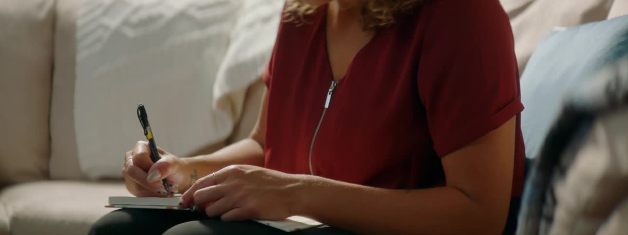 Young woman scrolls on laptop then writes in journal