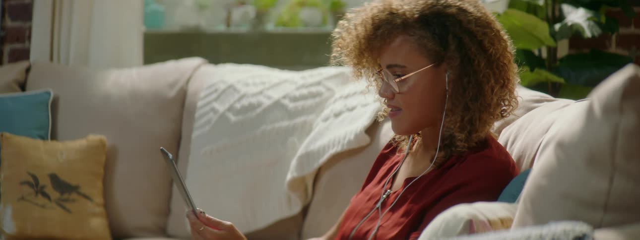 Young woman wearing glasses smiles while on a video call in her smartphone