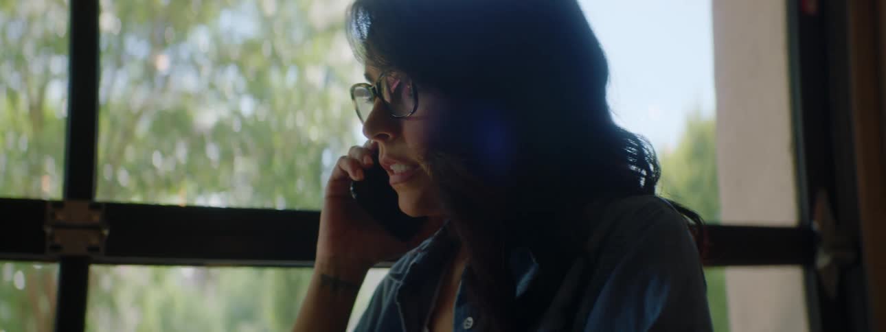 Woman wearing glasses talks on her smartphone while sitting in a restaurant