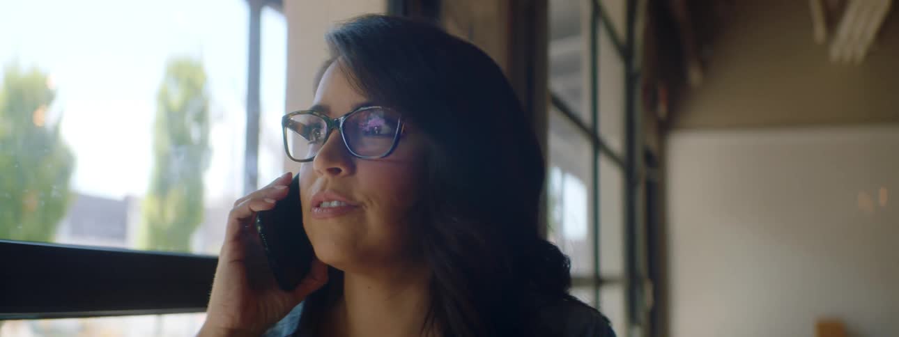 Young woman wearing glasses talks on the smartphone in a restaurant