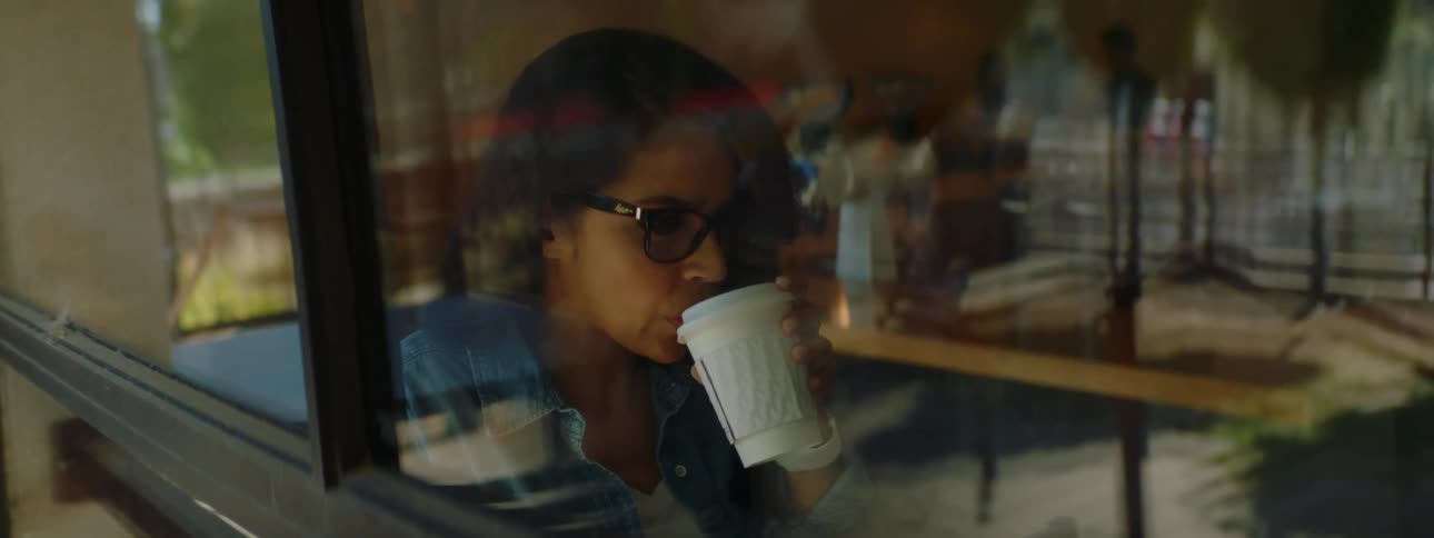 A woman with glasses sitting in a coffee shop using a laptop
