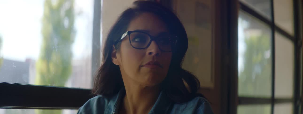 A woman with glasses sitting at a table typing on a laptop