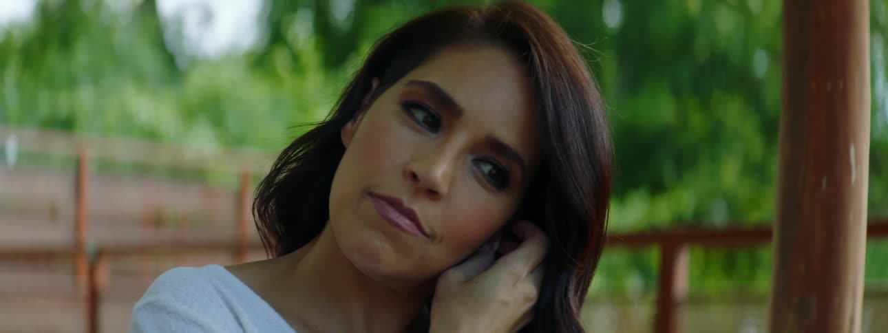 A woman sitting outside with her laptop takes her ear buds out of her ears