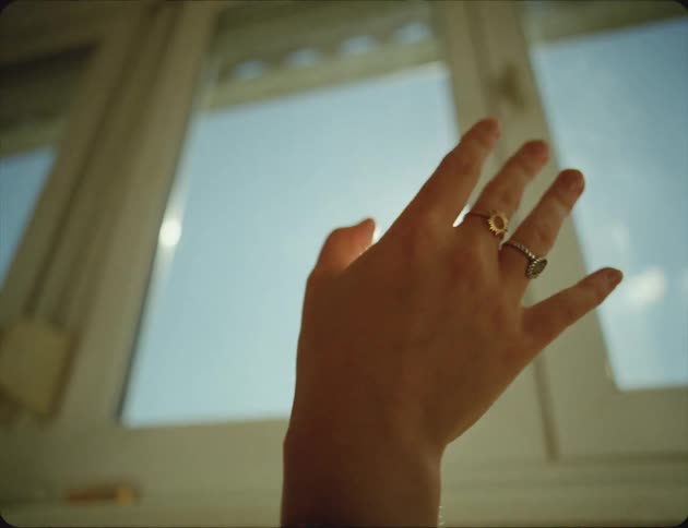 A person is wiggling their fingers in front of the window