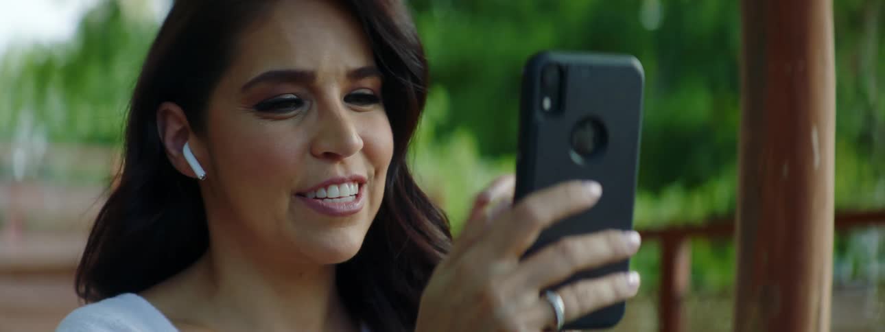 A young woman waves at her cell phone as she video chats