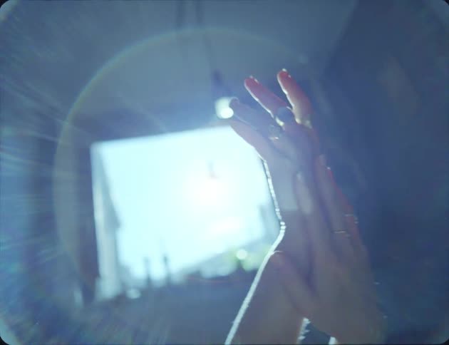 A teenage girl at home holds her hands up in the air and rubs them together and moves them around