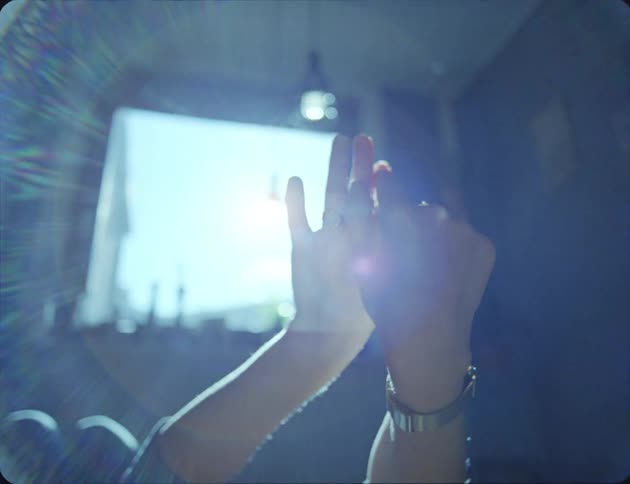 A womans hands with rings with a light bulb and a window in the background