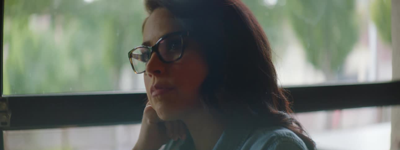 A woman with glasses sitting at a table typing on a laptop