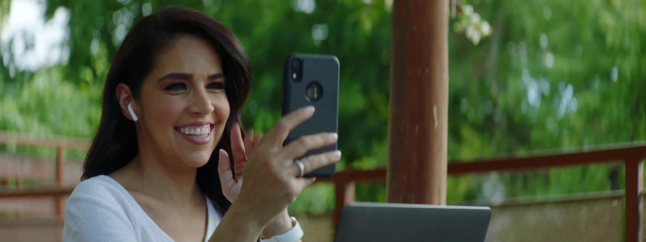 Young woman using cell phone to video chat on patio outdoors