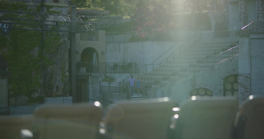 A man and woman holding hands walk down stairs in an outdoor area