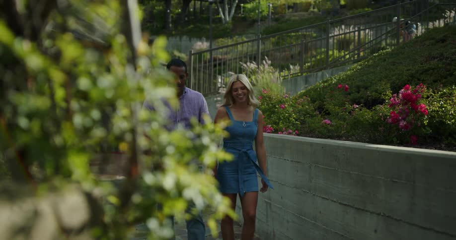 A man and woman hold hands and laugh as they take a walk through their neighborhood