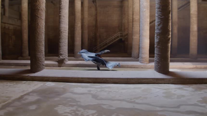 A woman in a costume spinning and dancing in a room with pillars
