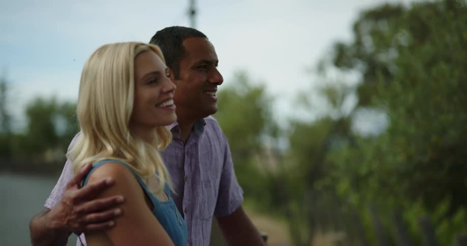 A man and woman point and laugh as they talk together outdoors during the day