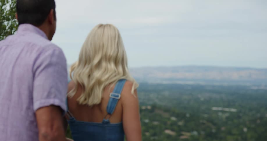A couple walk over to take in the view from the mountain top