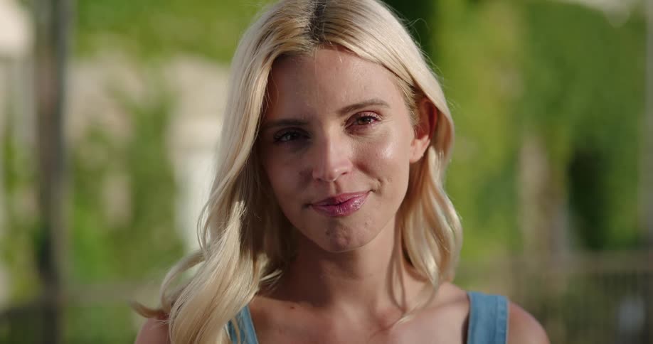 Blonde woman looks at the camera and smiles broadly