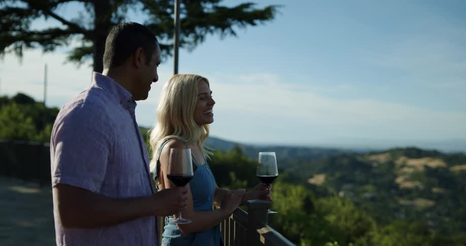 A man and a woman standing and talking while holding glasses of wine
