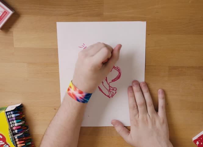 An artist uses a crayon to draw on a sheet of paper