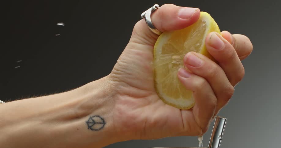 A person squeezes the lemon into the glass