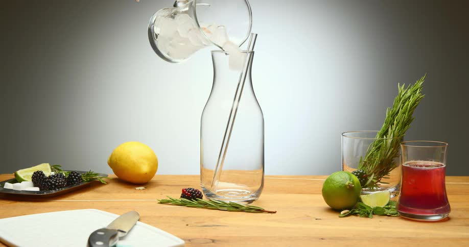 A person pouring ice and water into a jar on a table