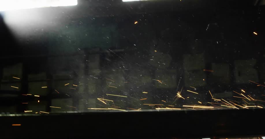Sparks are flying and smoke is rising from work being done in a metal workshop