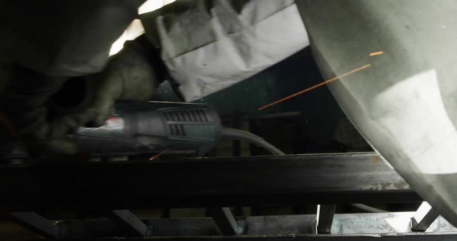 Person wearing protective gear uses power tool on metal railing creating sparks