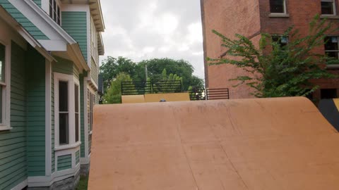 A teenage girl jumps her bike over ramps set up in a neighborhood
