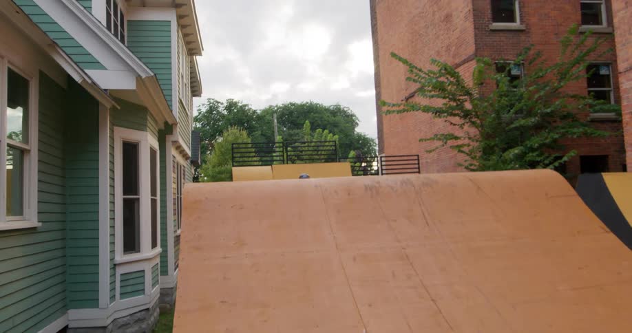 A teenage girl jumps her bike over ramps set up in a neighborhood