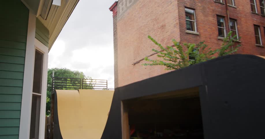 Woman rides bike along man made bike path including jump near apartment buildings