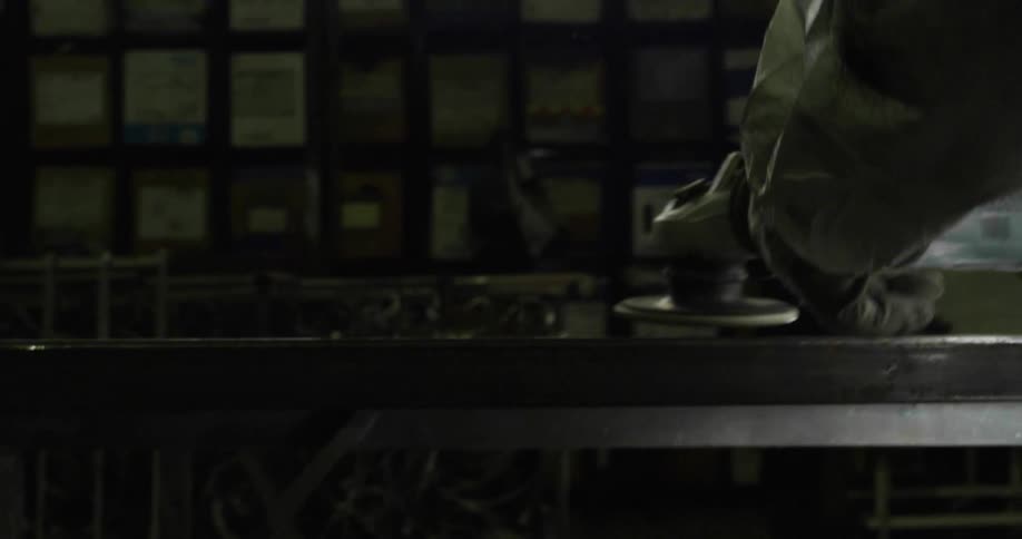 Person wearing protective gear works on metal railing with grinder creating a shower of sparks