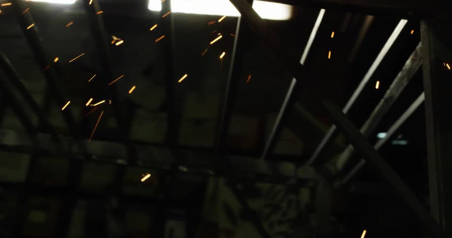 Person wearing protective gear polishes metal railing with power tool creating shower of sparks