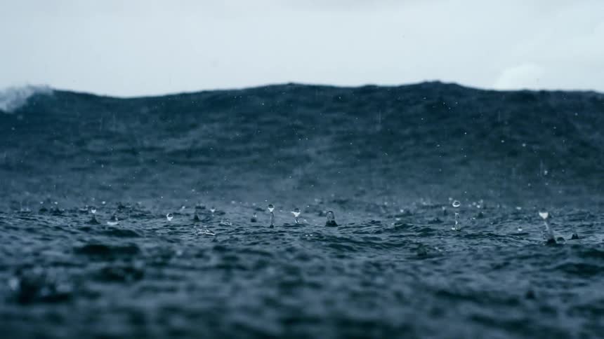 Rain falls on the ocean as large waves swell