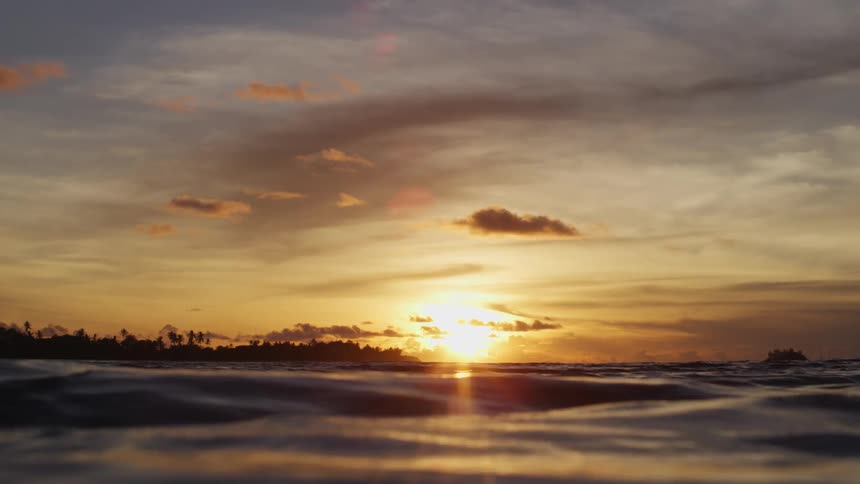 The low sun shines down on the rolling waves of the ocean