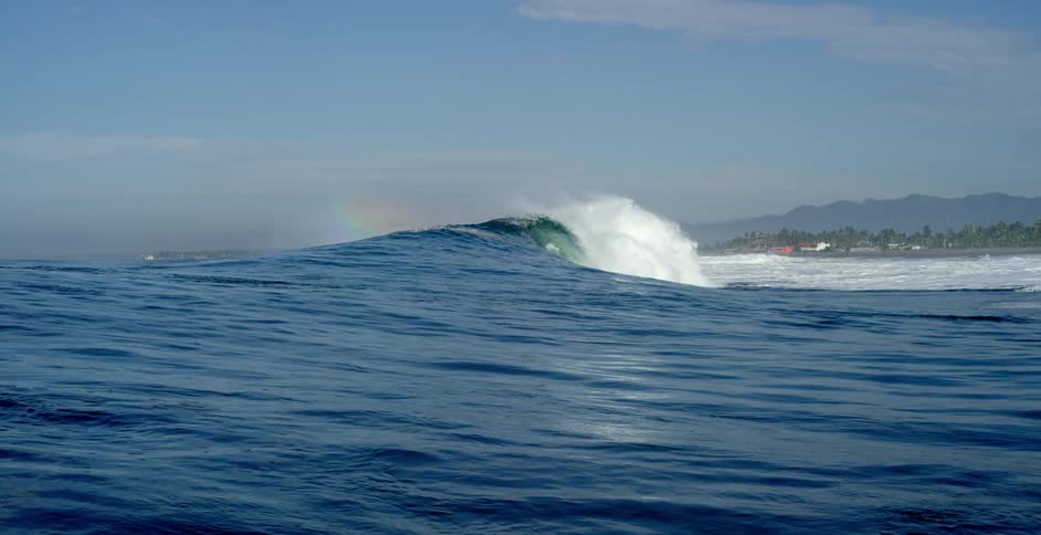 An ocean flowing and crashing towards a beach in the daytime
