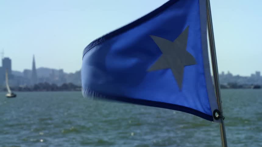 A blue flag with a white star on a boat flaps in the breeze