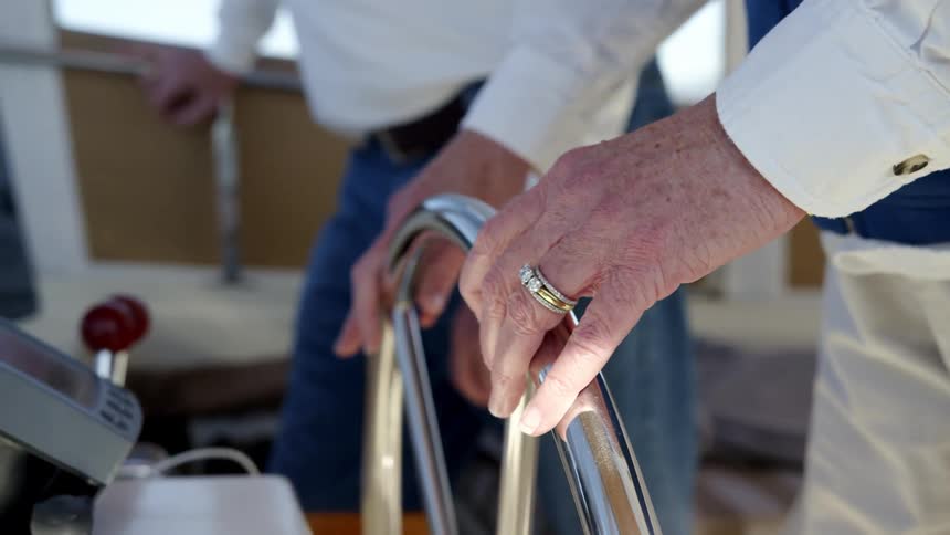 An elderly woman steers a boat as a man stands beside her