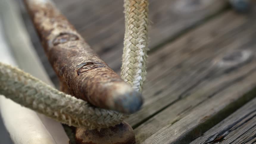 A mooring line slides along a rusted dock cleat